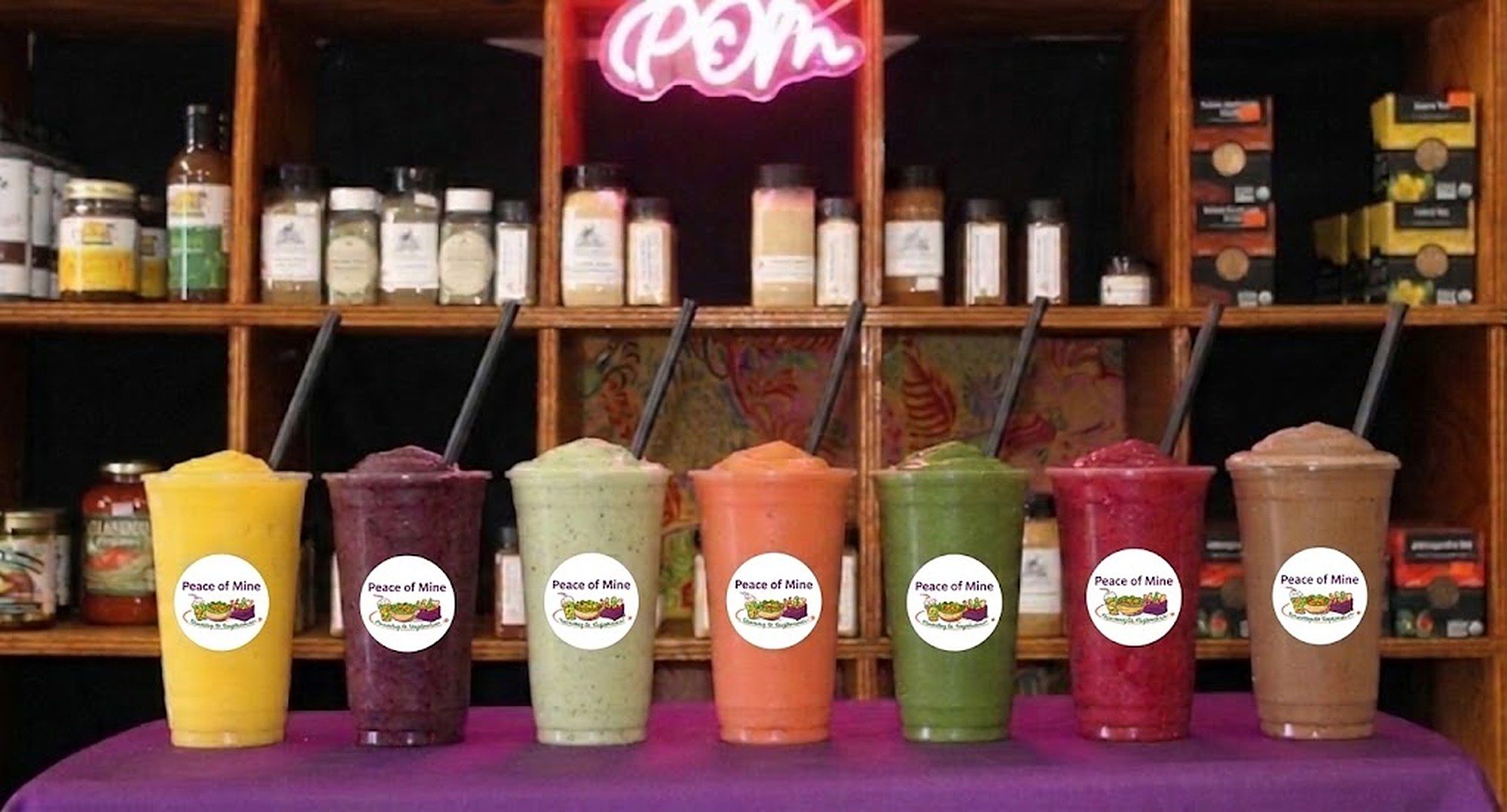 Seven Peace of Mine sea moss smoothies lined up on the counter: Mango Tango, Go Berry, Winters Paradise, Tropical Blast, V-Tox, Peace of Mine and Sunflower Power
